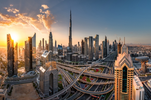 The Dubai skyline with a large swirling highway in the foreground and skyscrapers in the background